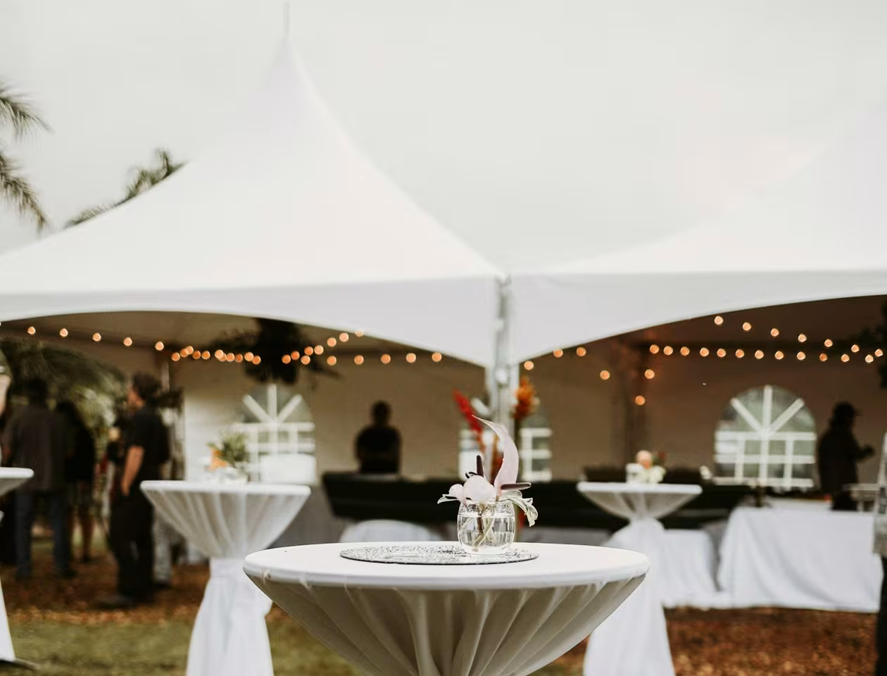 Elegant stretch tent event setup with floral table centerpieces and white canopy