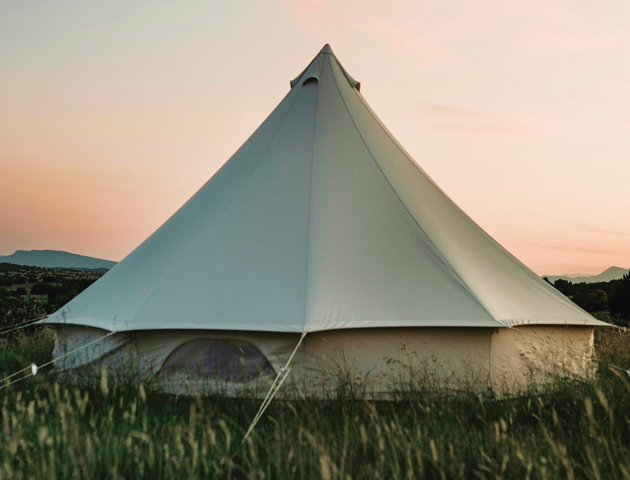 Freeform stretch tent providing shade over an outdoor countryside gathering